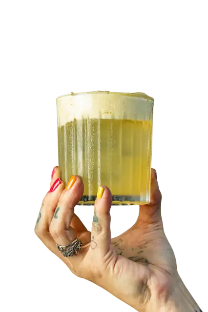 Mão com unhas coloridas erguendo um coquetel com espuma