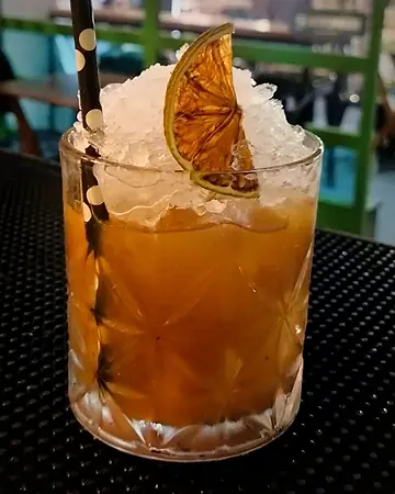 Coquetel com gelo triturado, laranja desidratada e canudo de bolinhas