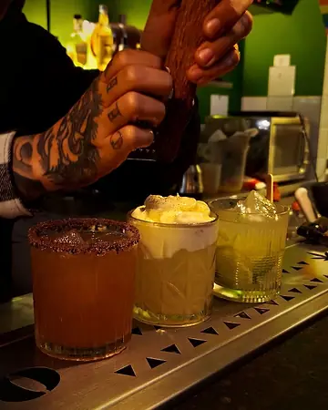 Bartender preparando três coquetéis no balcão