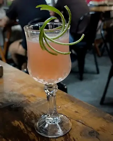 Coquetel rosado em taça de cristal com espiral de casca de limão