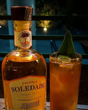 Garrafa de cachaça Soledade Jequitibá ao lado de um highball